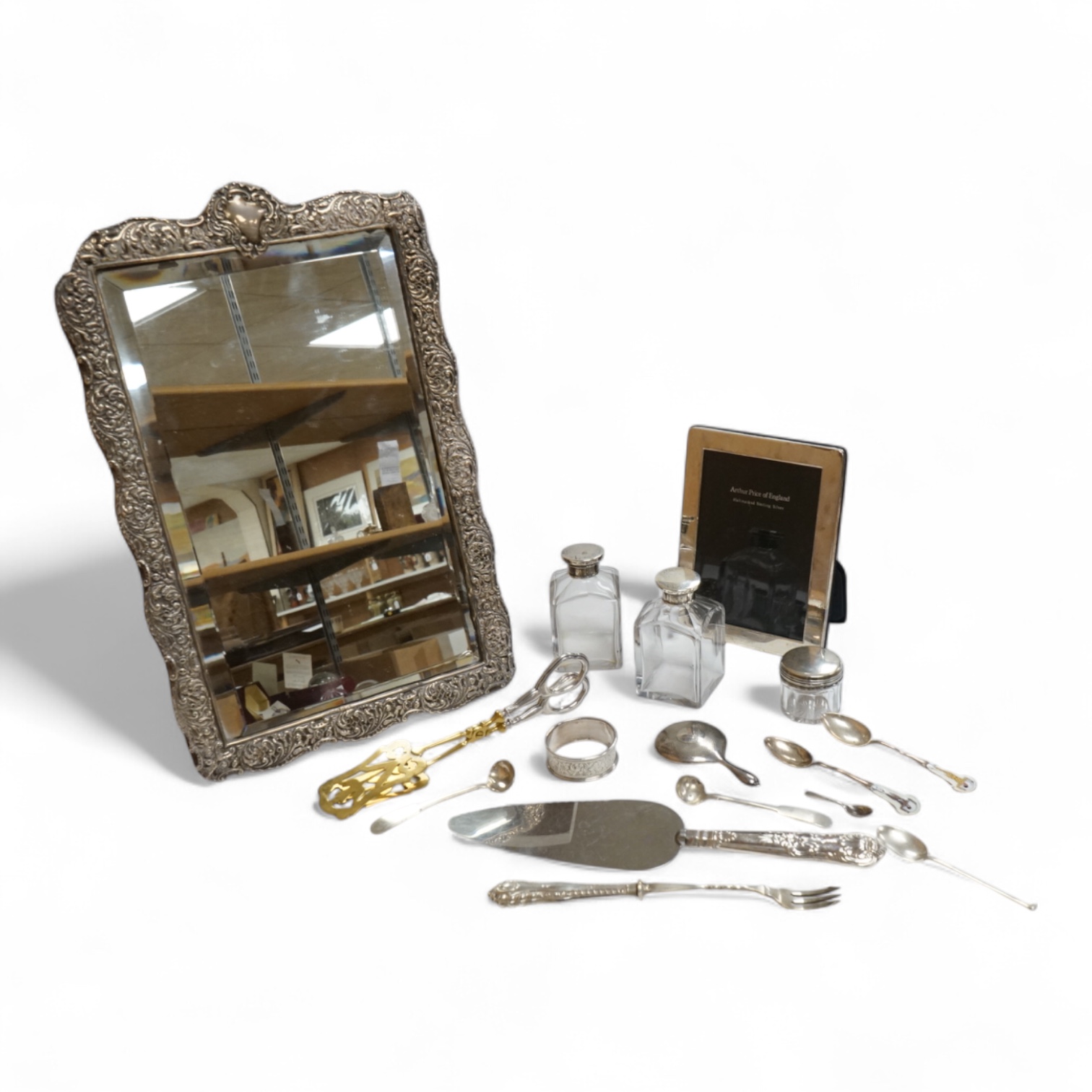 A late Victorian repousse silver mounted rectangular easel mirror, Birmingham, 1896, 35.7cm(a.f.), together with a modern silver mounted photograph frame, a silver handbag mirror/compact, three mounted glass toilet jars,